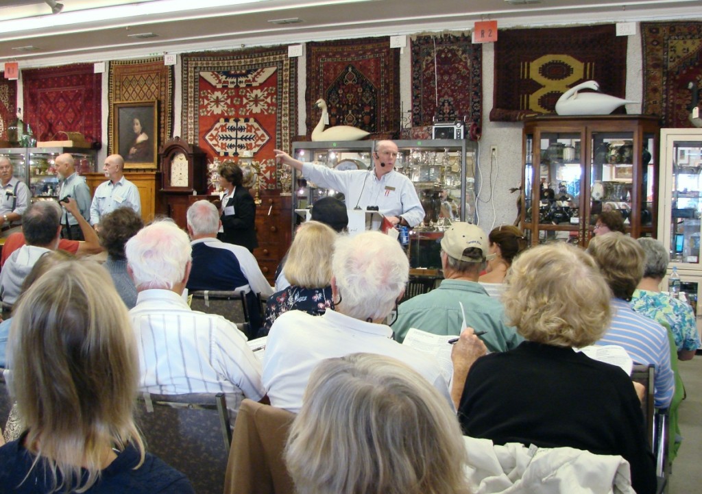 Bob Foster is shown at the podium with some of the day’s offerings behind him. He runs a fast-paced sale, moving close to 100 lots an hour.