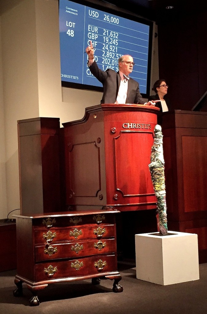 Auctioneer John Hays looks for bids on a fiber construction, $32,500, by Outsider artist Judith Scott. Below left, a 1770–90 Massachusetts serpentine front chest of drawers from the Rosebrook collection, $35,000.