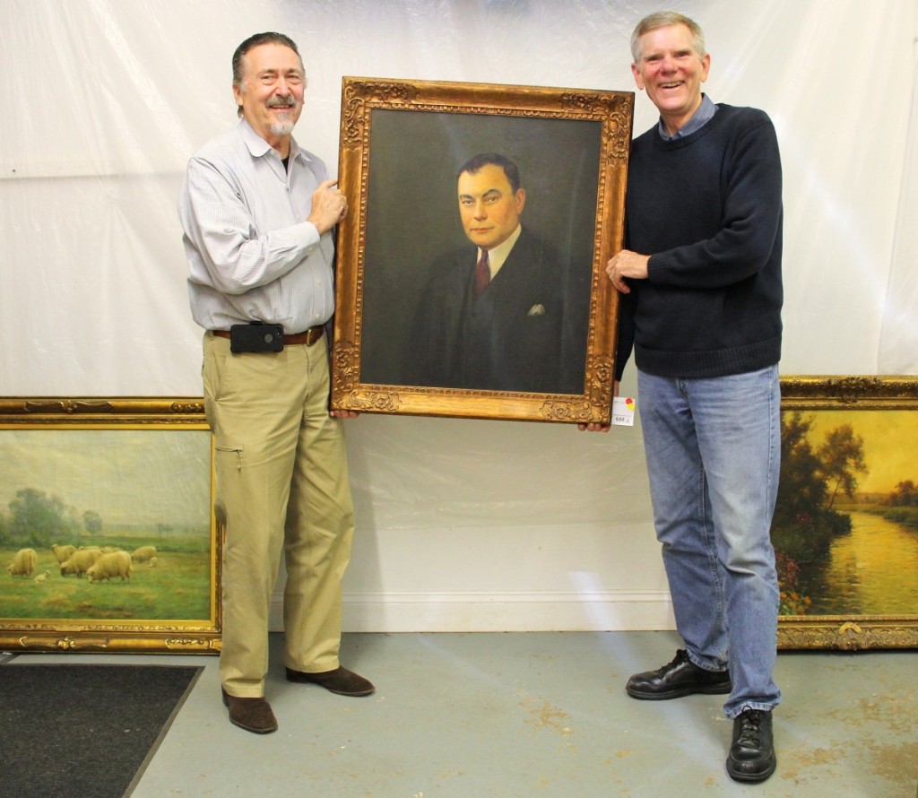 Auctioneer Tom Schwenke, left, and Brock Jobe, Winterthur curator emeritus, hoist a portrait of C.K. Davis (1889–1968), past president of DuPont subsidiary Remington Arms and a mid-Twentieth Century collector of American antiques. The auction featured roughly 75 lots inherited by Davis’s son William. Also among the Davis consignment, “May Morning” by John Carleton Wiggins, $2,440, and, right, “Evening Beaumont-le-Roger” by L. Aston Knight, $4,575.