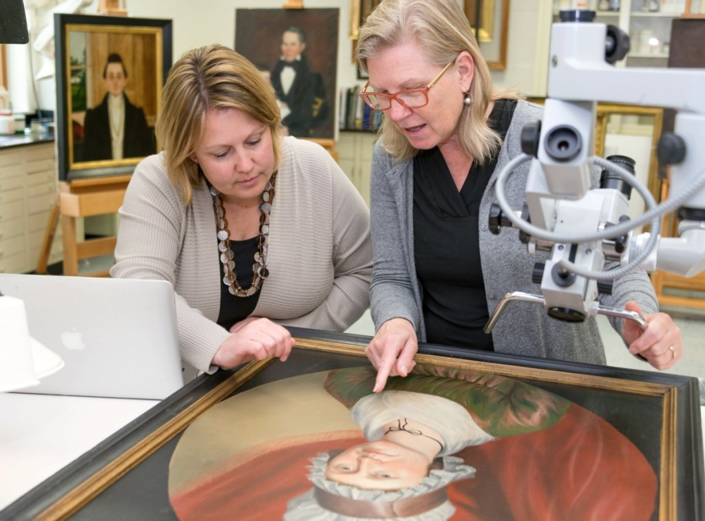 Laura Pass Barry, left, Colonial Williamsburg’s Juli Grainger curator of paintings, drawings and sculpture, and Shelley Svoboda, senior conservator of paintings, examine the circa 1800 portrait of Matilda Morrow by Charles Peale Polk. —Jason Copes photo