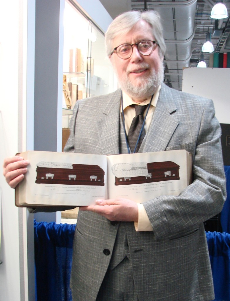 Catalogs published by Forrest Proper, Joslin Hall Rare Books, Northampton, Mass., often include titles relating to funerals. He’s holding a 1922 trade catalog, with 260 pages, issued by the National Casket Company. It is filled with black and white and color illustrations of the many caskets offered by the company and was priced at $275. —ABAA Boston Book Fair