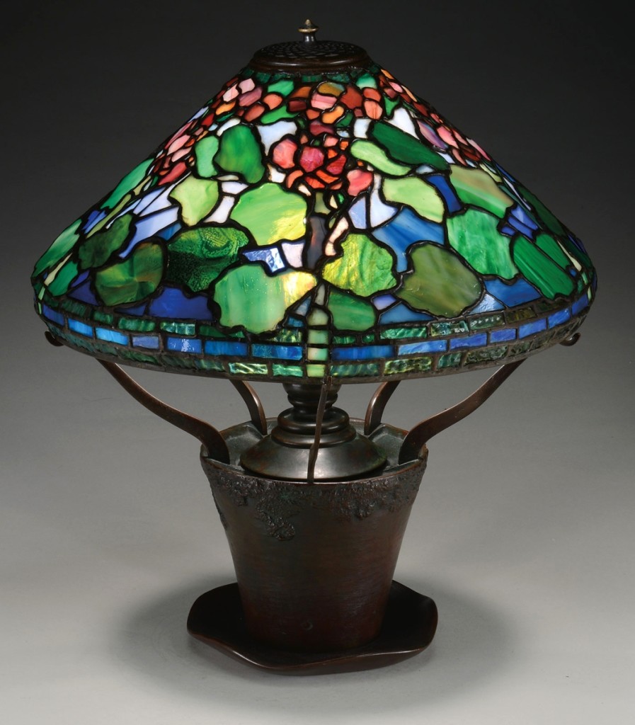 The signed Tiffany Studios Geranium pattern lamp, with a 16-inch shade, had red geraniums and mottled green leaves against a striated blue white background. It was one of three lamps that realized $84,700.