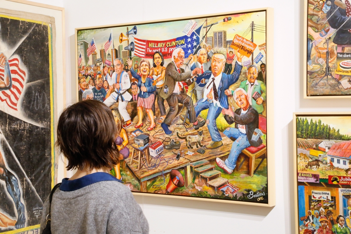 A viewer takes in a colorful and energetic work by Kenyan artist Joseph Bertiers in the booth of Ernie Wolfe Gallery, Los Angeles. Bertiers focuses on international politics and pop culture.