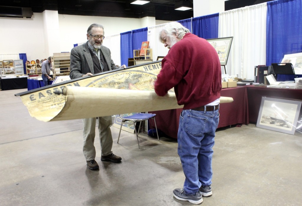 Greg Gibson, left, of Ten Pound Island Book Co., Gloucester, Mass., and dealer Bob Seymour unfurl a monumental map of the eastern hemisphere with a wealth of information on early expeditions, which Seymour eventually purchased and took home to study.