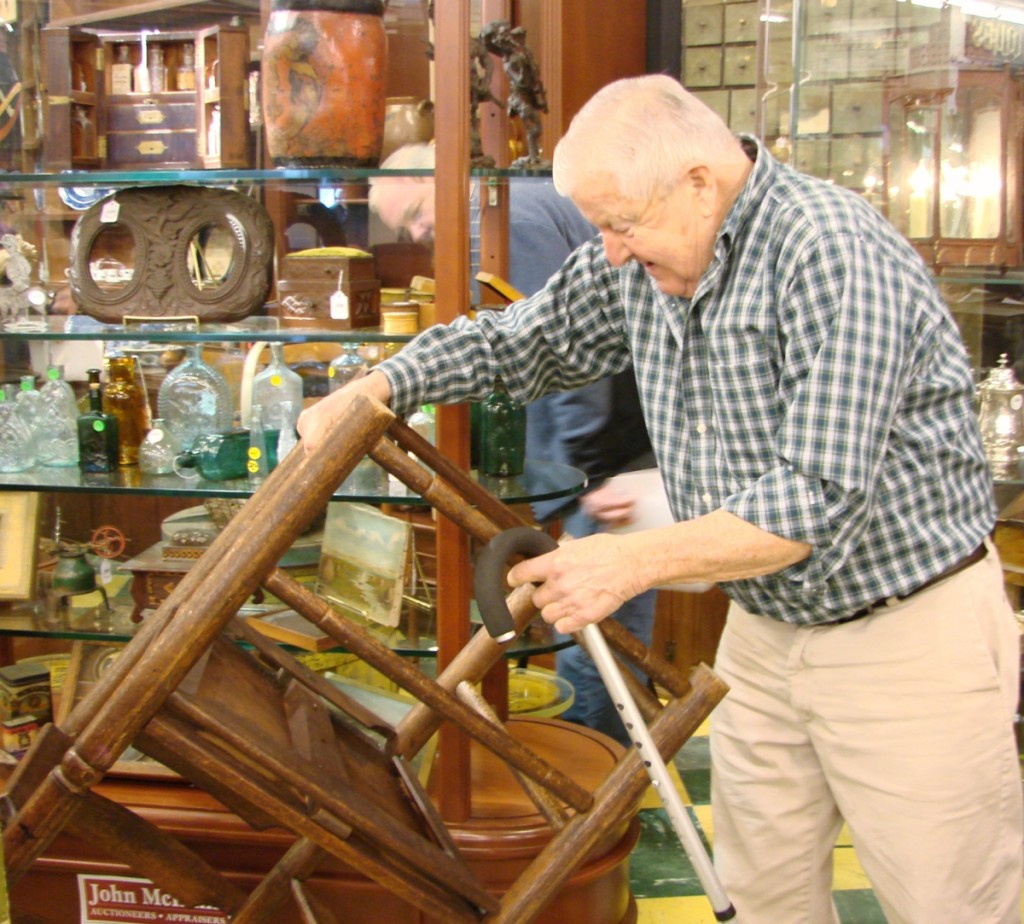 Carl Stinson bought several pieces of early furniture at the sale. Here he examines a Carver chair made by the Atwell Company.