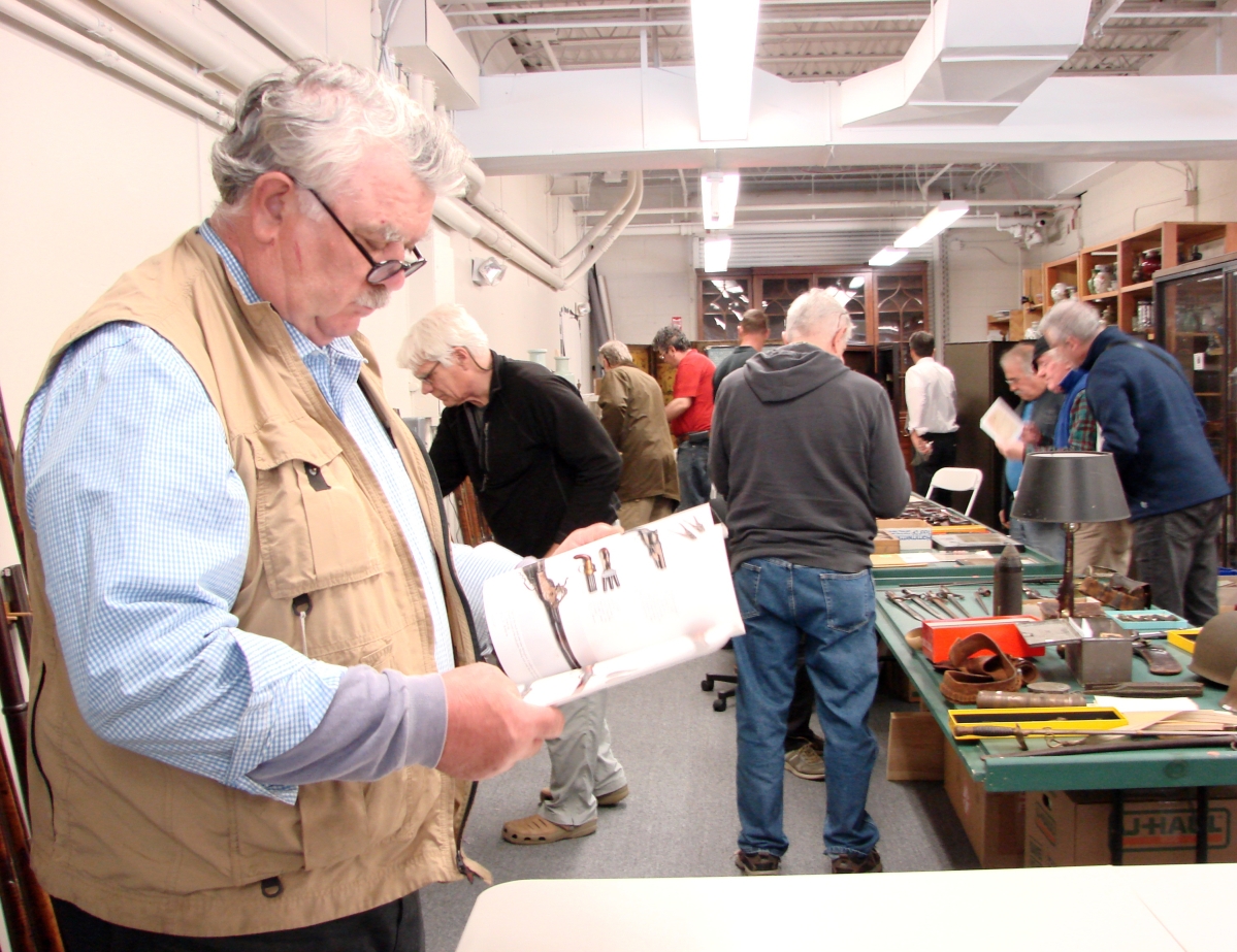 Dealer Hilary Nolan and several others look closely at the firearms prior to the first day of the sale.