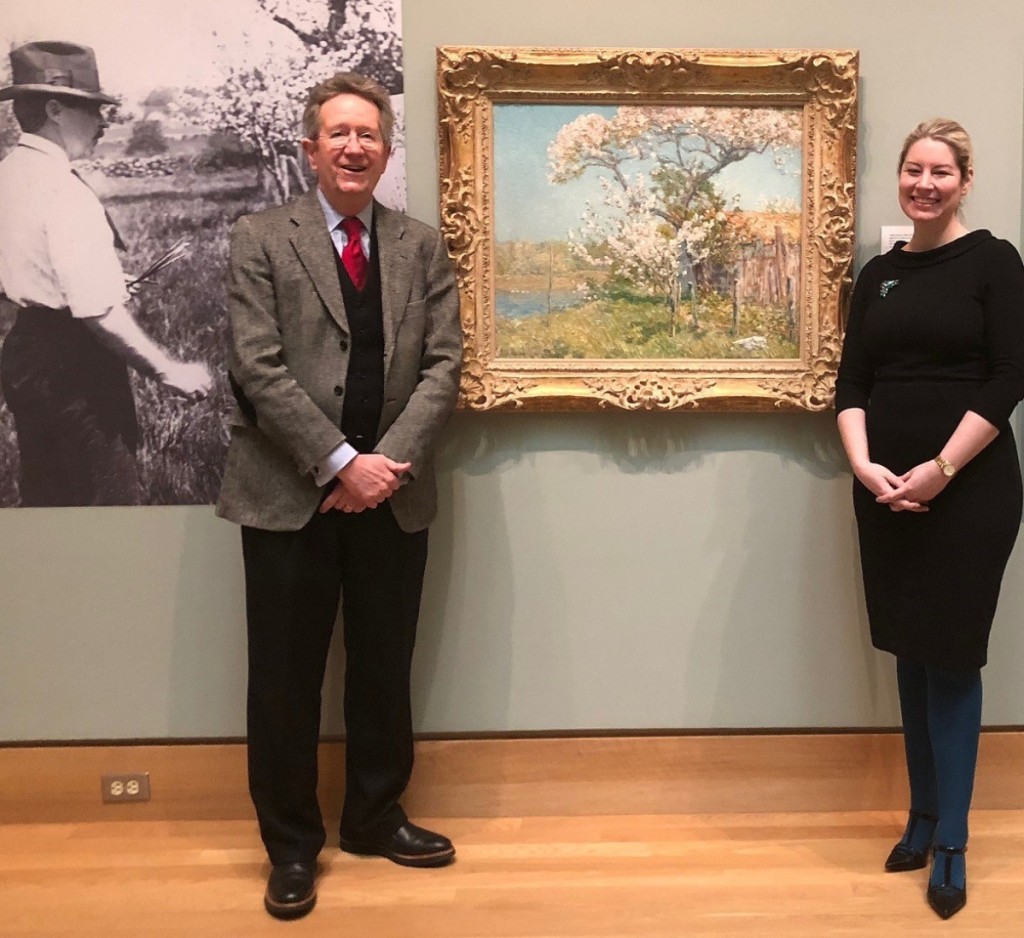 Florence Griswold Museum director emeritus Jeffrey Andersen and director Rebekah   Beaulieu with “Apple Trees in Bloom, Old Lyme” by Childe Hassam (1859–1935), 1904.   The Lieutenant River is seen left; Hassam’s studio, right, in this painting on panel given   in Andersen’s honor by the Vincent Dowling Family Foundation. From the museum’s   Lyme Historical Society Archives, the photo, left, shows Hassam at work on the oil.