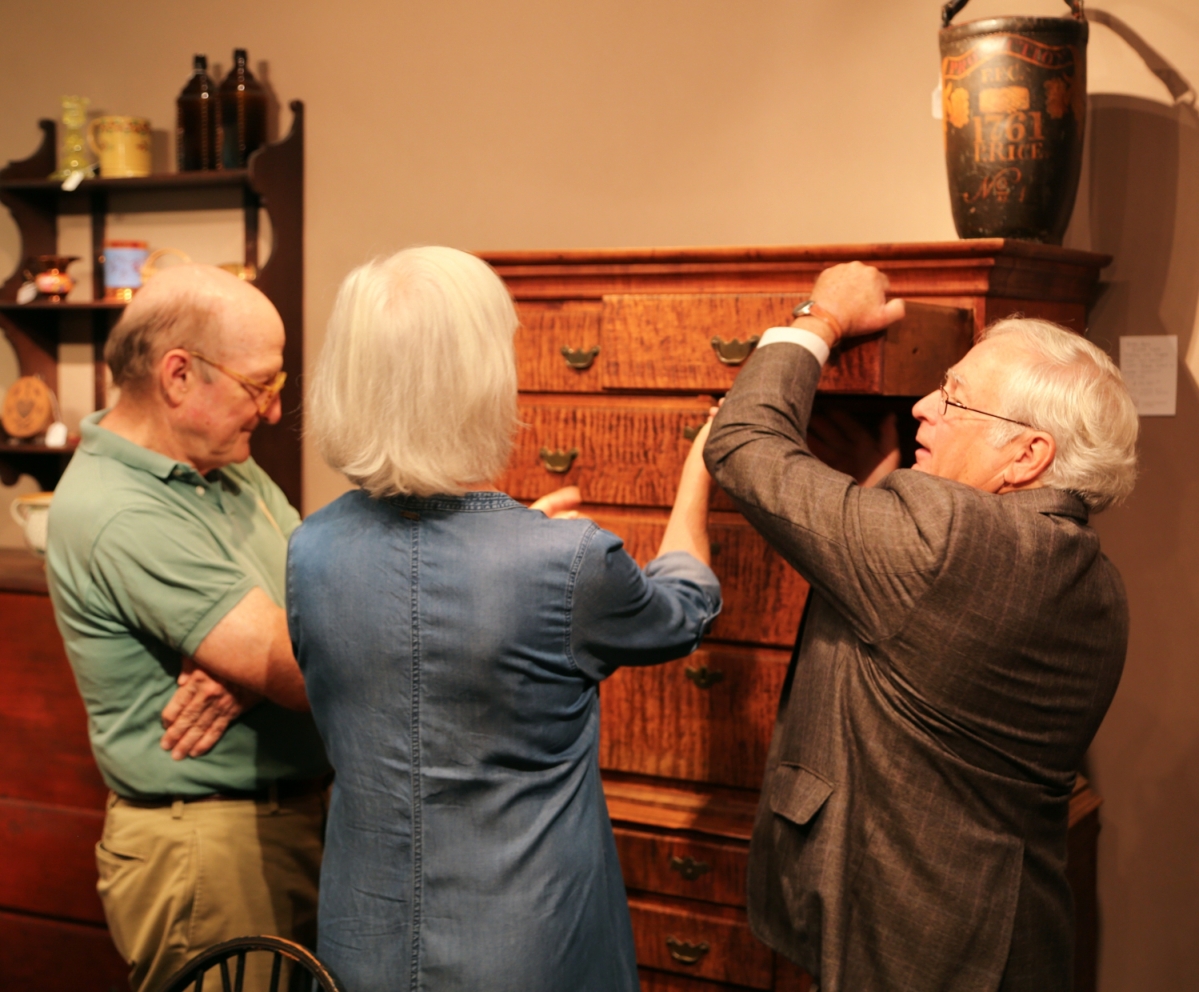 Arthur Liverant pulls a drawer from a Queen Anne figured maple highboy to show a client. The piece was from Rhode Island or Eastern Connecticut, 1735–1750.
