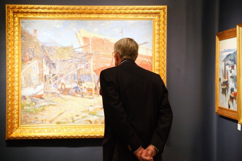 A buyer admires some of the Cape Ann paintings in the booth of Parco Fine Art, Ipswich, Mass.