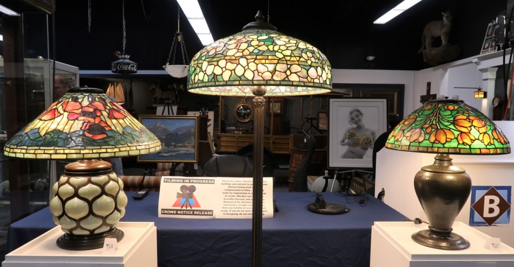 Three Tiffany Studios lamps from a Houston collection grossed $250,800. From left, a circa 1910 table lamp with a Poppy shade and a blown-glass and bronze base, $108,000 ($80/120,000); a circa 1910 bronze and glass floor lamp with a Dogwood shade, $114,000 ($90/120,000); and a circa 1915 table lamp with a Crocus shade on a bronze pine needle pattern base, $28,800 ($25/35,000).