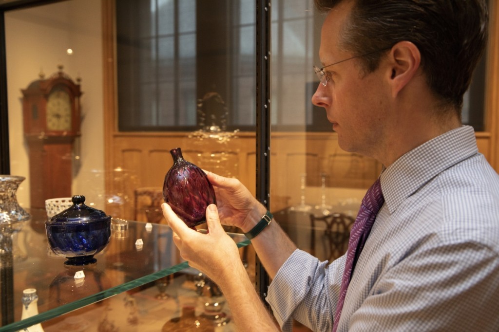 Curator John Stuart Gordon inspects a pocket bottle possibly made by Henry William Stiegel at the American Flint Glass Manufactory in Manheim, Penn., between 1764 and 1770.