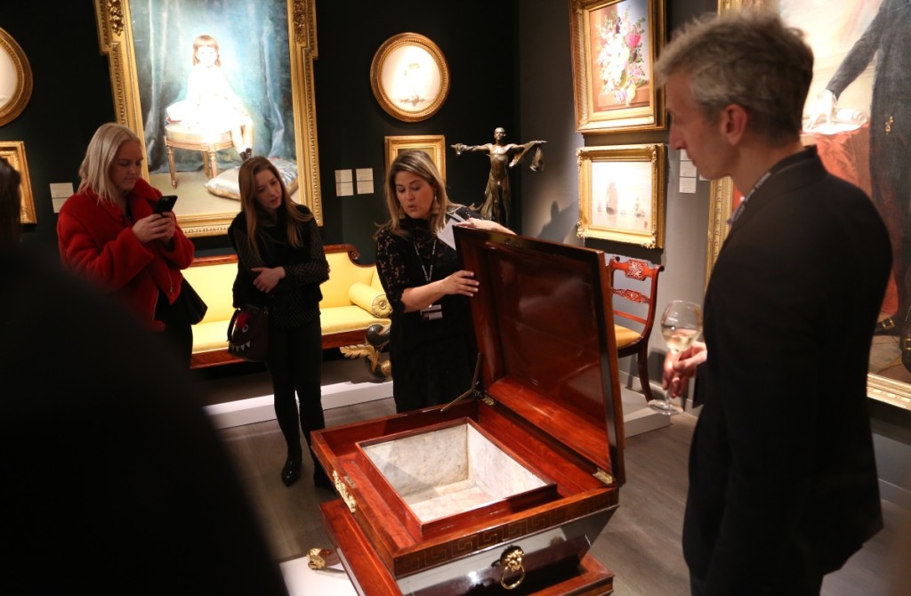 Elizabeth Feld, Hirschl & Adler Galleries, New York City, seen here during a booth talk discussing the merits of a circa 1815 Classical mahogany wine cooler attributed to Thomas Seymour.