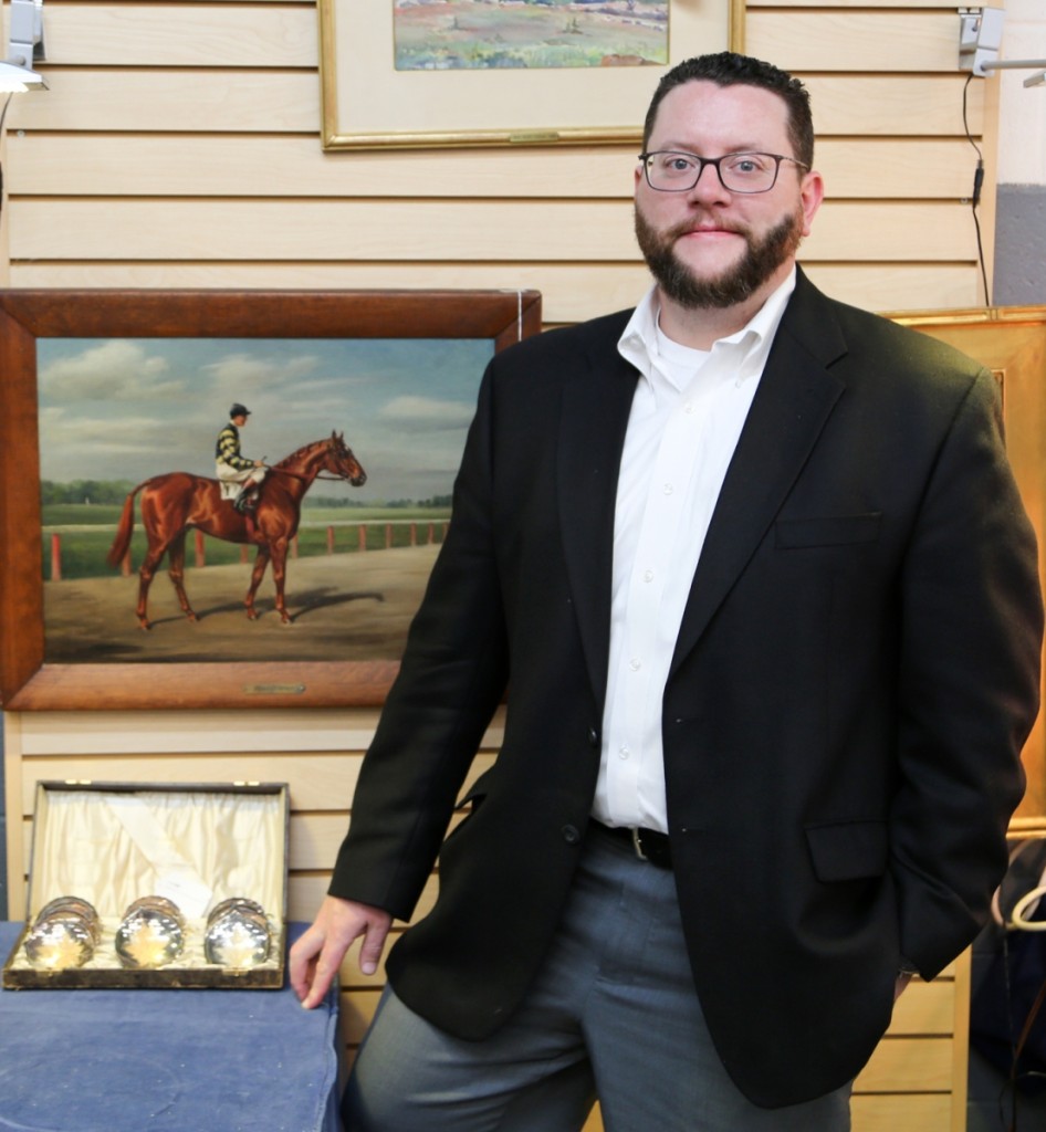 Auctioneer Ryan Brechlin stands beside an oil on canvas portrait by Franklin Brooke Voss featuring famed racehorse Man O’ War. The portrait sold to a private collector for $55,200.