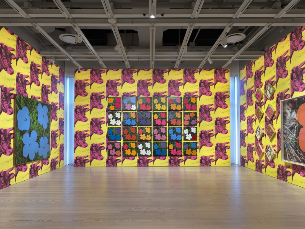 Installation view of “Andy Warhol – From A to B and Back Again” at the Whitney Museum of American Art, New York. Back wall featuring 24 variations of “Flowers,” 1964; Left wall featuring “Flowers [Large Flowers],” 1964–65. Photograph by Ron Amstutz. ©2018 The Andy Warhol Foundation for the Visual Arts, Inc / Licensed by Artists Rights Society (ARS), New York.