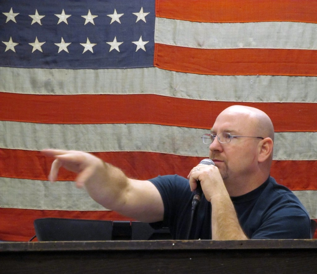 Auctioneer Kurt Kilgore works against a backdrop of a military-base-size, 48-star American flag.