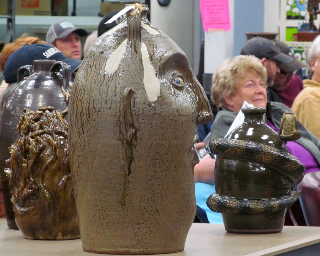 Clint Alderman’s 10-gallon double handle face jug appears to be watching the action from a display table in the center of the bidder’s seating area. He brought a respectable $900 when his turn came.