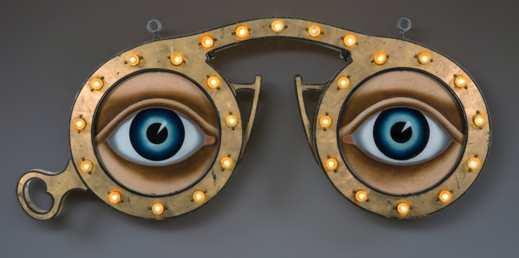 Optician’s trade sign, E.G. Washburne & Co., 207 Fulton Street, New York City, circa 1915. Paint and gold leaf on zinc and iron, with glass and light bulbs; 26 by 54 by 4 inches. Collection of Penny and Allan Katz.                —Gavin Ashworth photo