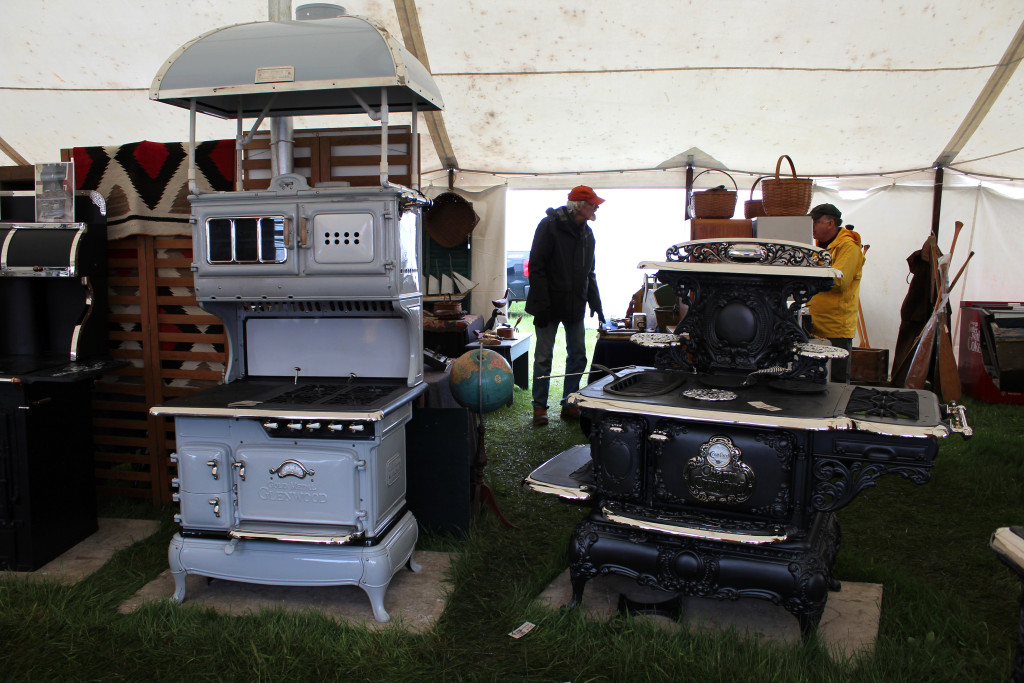 Two restored stoves with David Erickson, Erickson’s Antique Stove, Inc., Littleton, Mass. The Glenwood model on the left had a manufactured hood was priced at $15,000 while the Crawford stove on the right was priced at $5,800. -Midway. 