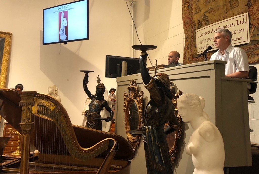 Surrounded by the marbles and decorative art items from the Sandra Clements collection, auctioneer Justin Garrett is offering what eventually becomes the top lot (on the screen).