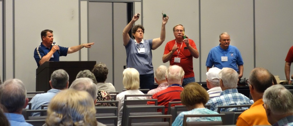 A highlight of the convention was an auction with club members offering banks for sale. As usual, Doug Riat called the auction, with Bill Dillon, upper right, holding items up to be seen. In the photo, right, Dolli Kettron holds a couple of banks way up high.