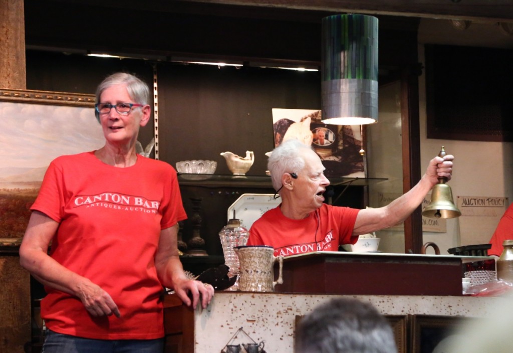 Richard Wacht auctions off the first lot of the sale, a brass schoolmaster’s bell, for $85. His business partner Susan Goralski stood next to the podium and called out bids the entire night.