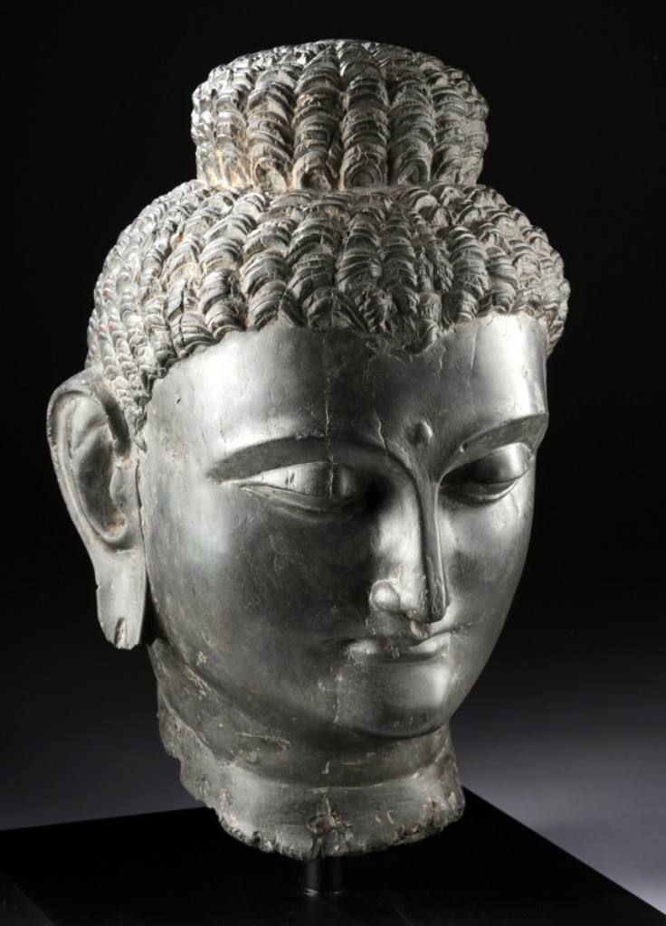 A larger-than-lifesize, finely carved and polished grey schist head of Buddha from Central Asia, Pakistan and Afghanistan, carved during the Gandharan Empire, circa 200 CE, 15½ inches high, with hair styled into a large ushnisha, garnered $34,238.