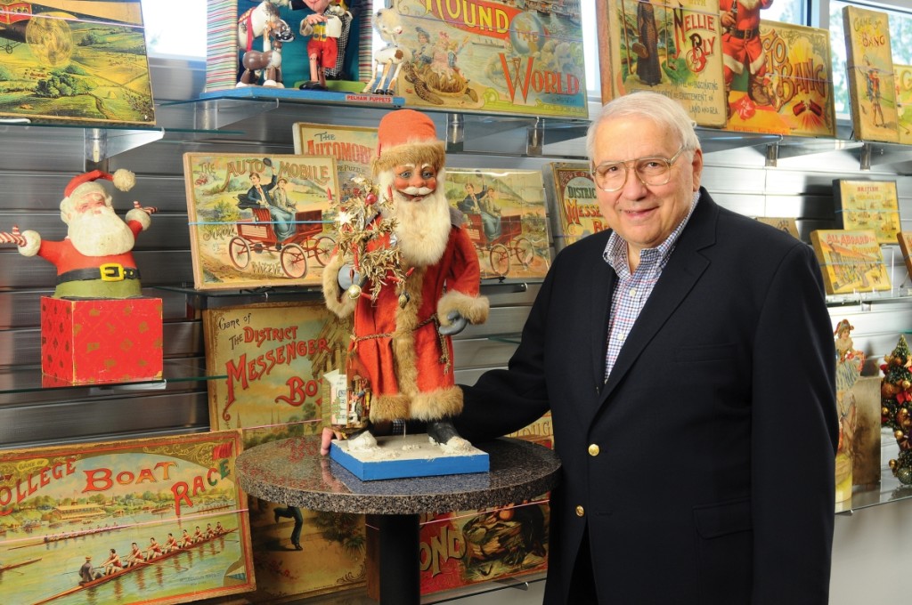 Tony Annese, surrounded by many of his lithograph paper on wood games, with one of his favorite Christmas pieces, an early nodding Santa with feather tree that brought $19,200 ($3/5,000). Courtesy Bertoia Auctions.