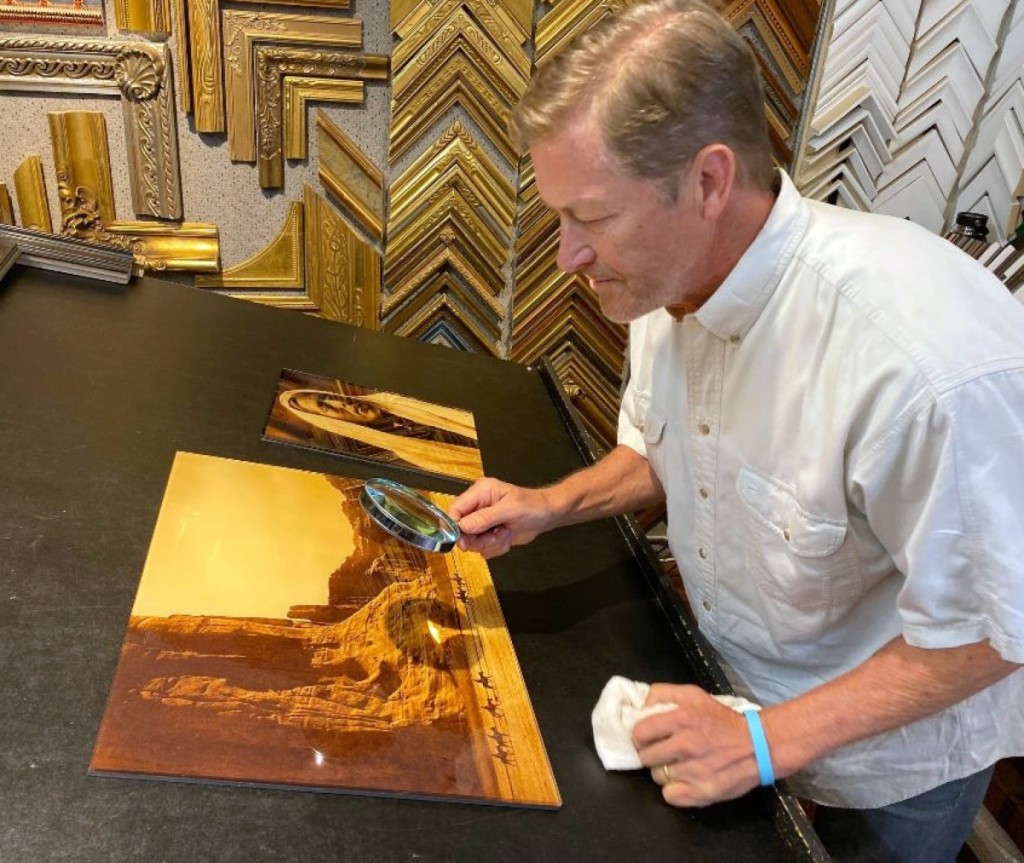 Paul Unks examines a gold tone of Curtis’ “Canyon de Chelly,” before framing.