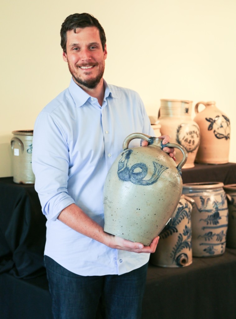 Luke Zipp, specialist and auctioneer, stands with the sale’s top lot in a stoneware presentation cooler with incised mermaid and seahorse motifs by Cornwall, N.Y., potter Moses Clark Bell. The cooler brought $70,800, selling to dealer Jim Kilvington in the gallery who was bidding on behalf of a client. It was only the third mermaid-decorated piece the firm had ever seen.