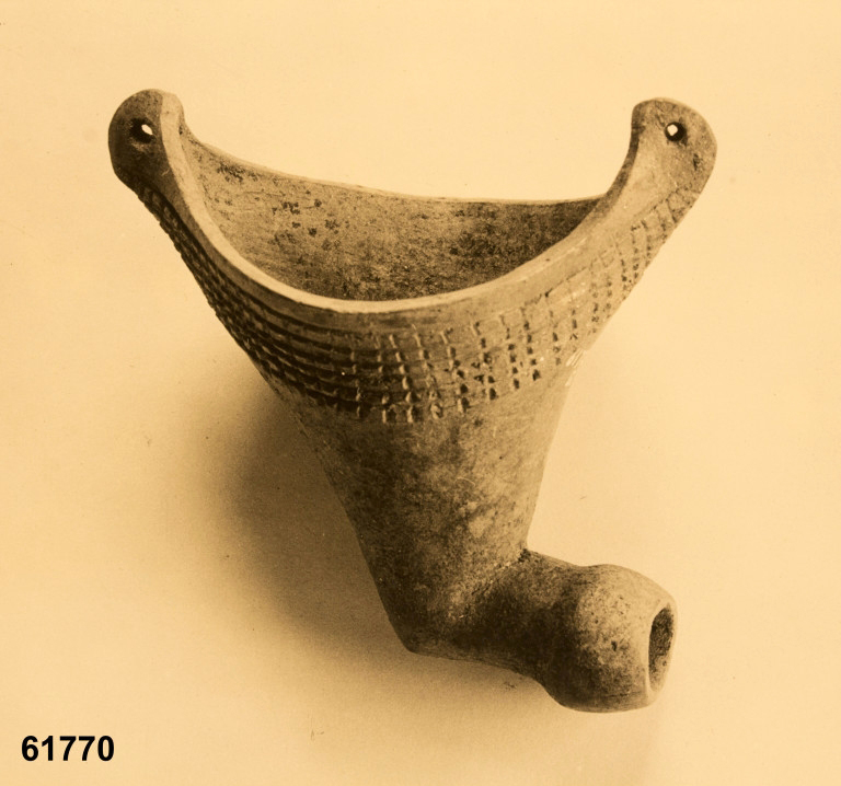 Effigy pipe. Excavated by Warren King Moorehead in 1927 from Grave 12, Etowah site (9BR01), Cartersville, Bartow County, Ga, USA. The ceramic smoking pipe is an effigy of a basket, canoe or pottery vessel. Approximately 3 inches high by 3 inches wide. Native American Mississippian culture circa CE 1400-1600.