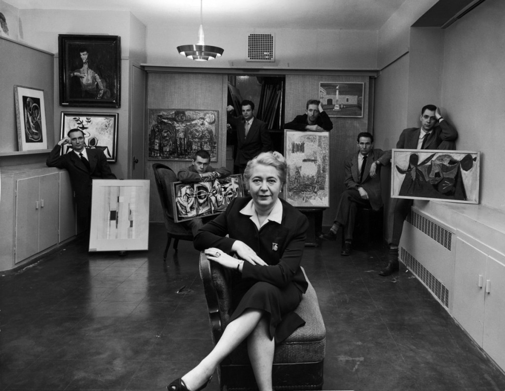 Edith Halpert at the Downtown Gallery, in a photograph for Life magazine in 1952. She is joined by some of the new American artists she was promoting that year: Charles Oscar, Robert Knipschild, Jonah Kinigstein, Wallace Reiss, Carroll Cloar and Herbert Katzman. Photograph ©Estate of Louis Faurer.