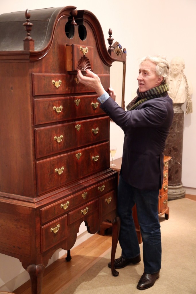 Auctioneer Leigh Keno examines the deep fan carving on the Samuel Gardner Salem, Mass., Queen Anne bonnet-top high chest of drawers. It went on to sell for $56,250.