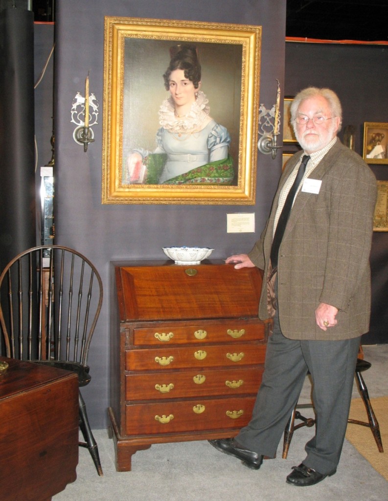 Lee Hanes stands in his booth, surrounded by American furniture, fine art and metalware.