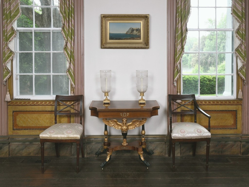 Here, in a photo staged by Brunk Auctions at Bankshaven, two Federal chairs flank the swivel-top card table possibly made by 1815-1820. Above hangs the 1856 oil on canvas “Beacon Rock, Newport” by John Frederick Kensett.