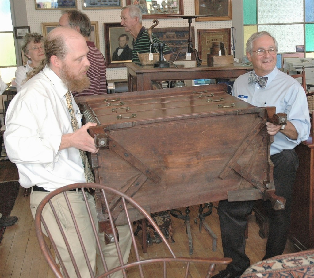 Weekly educational forums bring people in the shop during the spring and fall. Here, Kevin and Arthur hoist a chest of drawers from Litchfield County, Conn., giving guests a view of its distinctive, cross-braced construction.