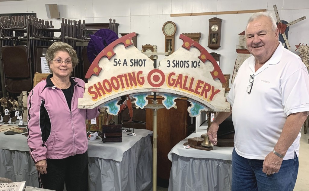 Del and Lou Roberson stand with their top lot, a wood painted Shooting Gallery sign that sold for $3,120. It sold to a collector.