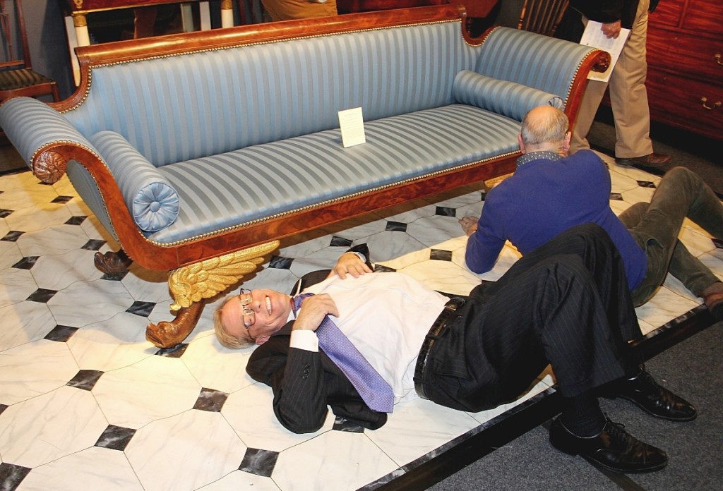 At the Philadelphia Antiques Show in 2017, Rebollo, left, and Clark Pearce got under the hood of a settee attributed to Isaac Vose & Son of Boston.                 —Laura Beach photo