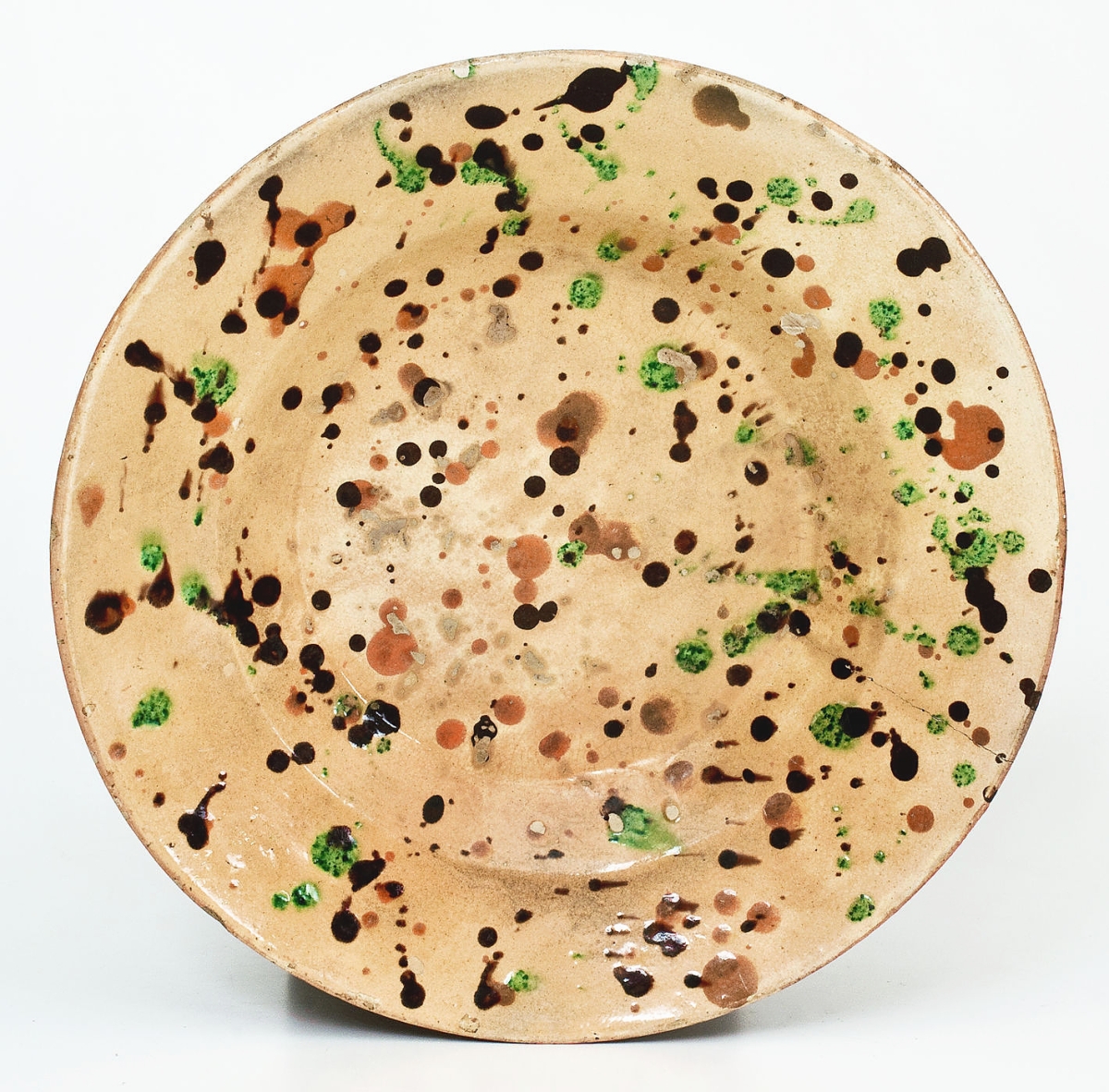 A remarkable spatter-decorated redware dish attributed to Solomon Loy of Alamance County, N.C., went out at $34,800. Cream slip under manganese, copper and orange slip spatters. 11¼ inches diameter.