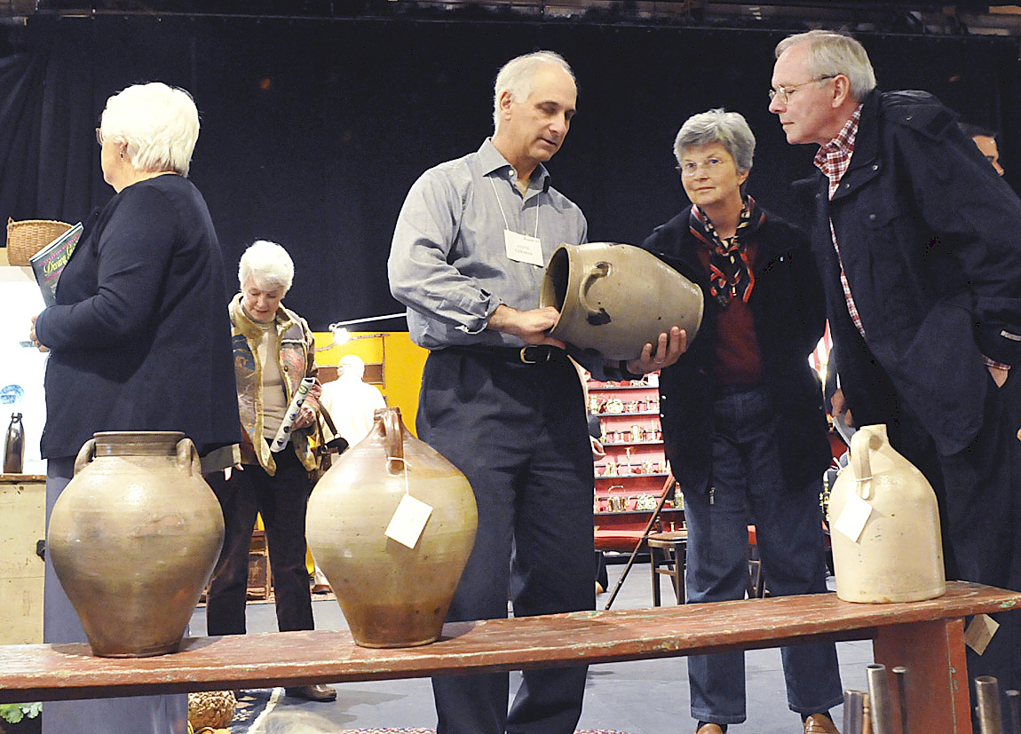 Steve German shows clients one of many pieces of stoneware that he had on display at the Weston Antiques Show, 2008. Photo David Smith.