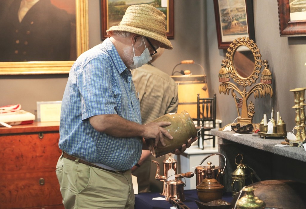 A buyer inspects a North Carolina redware jar for sale at Ponzi’s Antiques, Trumansburg, N.Y.