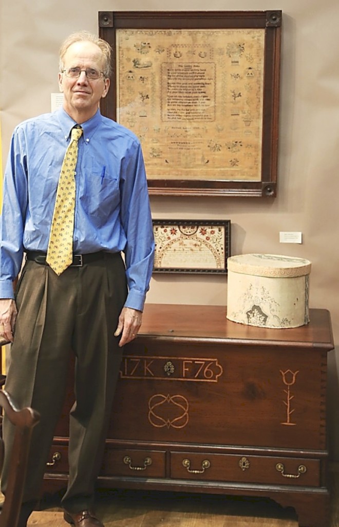 Philip Bradley stands before a 1776 Chester County chest-over-drawers in walnut with mixed-wood inlay. The large 1827 needlework at the top came in its original mahogany frame and was worked by Hannah Levis (1810-1836). Antiques and The Arts Weekly photo.