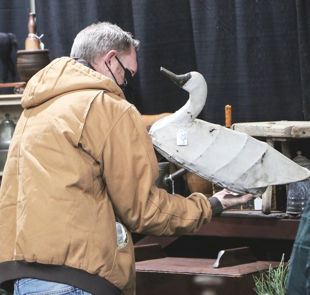 A buyer looks at a canvasback swan in the booth of Ye Olde Farmhouse Primitives, Stafford Springs, Conn.