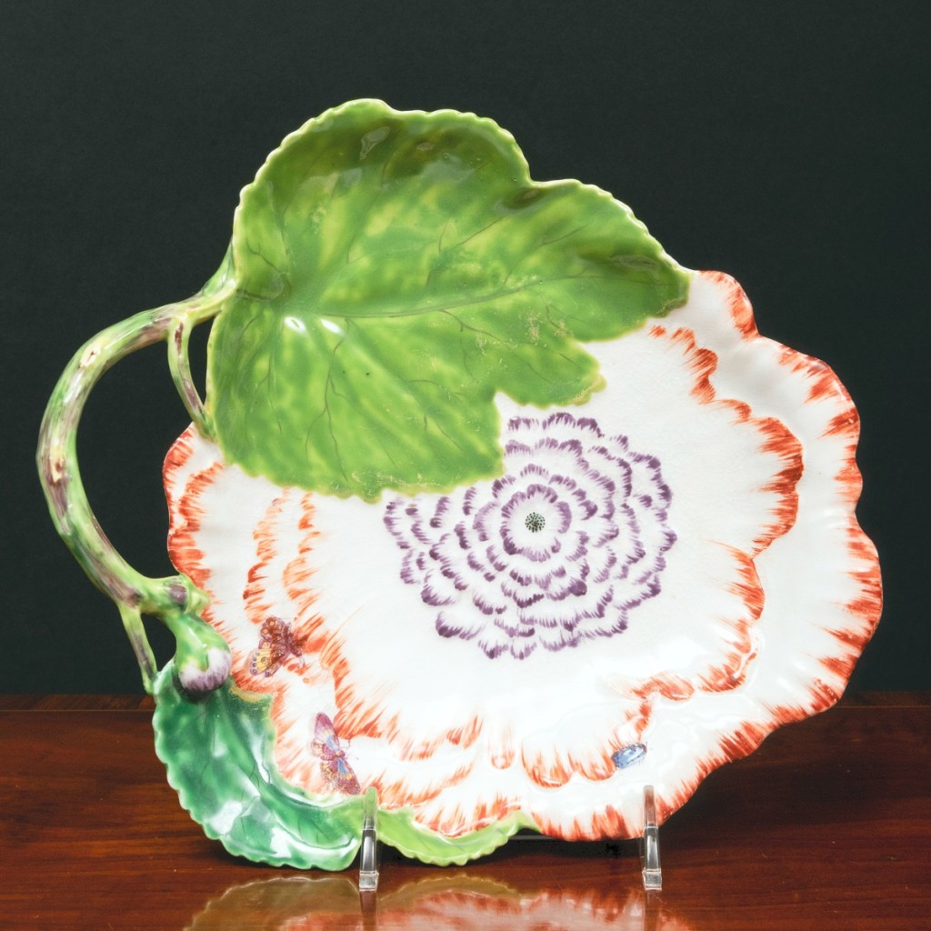 A single Chelsea porcelain flower dish forming a handled leaf with large blossom featuring orange edging and lavender center, unmarked, brought $7,040.