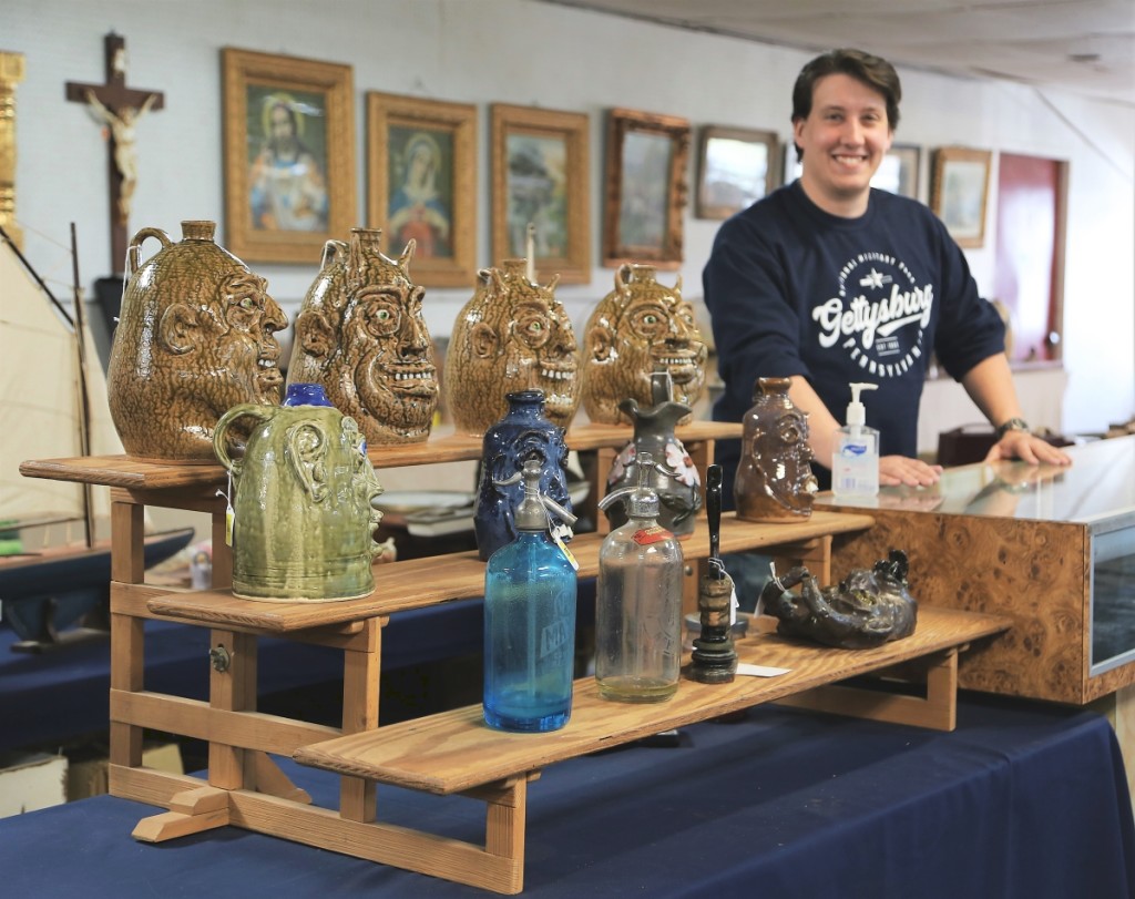 Auction assistant Taylor Hooey of Coventry, Conn., stands beside four separate lots of figural head jugs, each of them signed by the artist. Sent up to auction from “the Carolinas,” according to Bruce Ingraham, most of these will be heading back down south. The selling prices varied between $173 and $288 per lot.