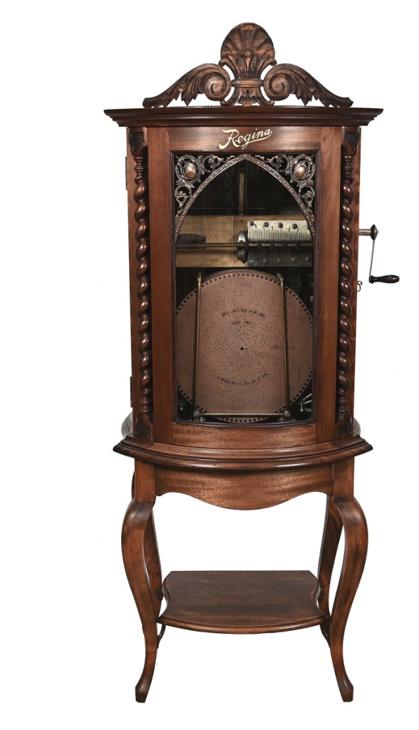 Regina upright music box, serial #3500107, fully operational, 22 15-inch discs, a mahogany case, curved glass, the original Regina label, double comb and a dial selector, realized $15,400.