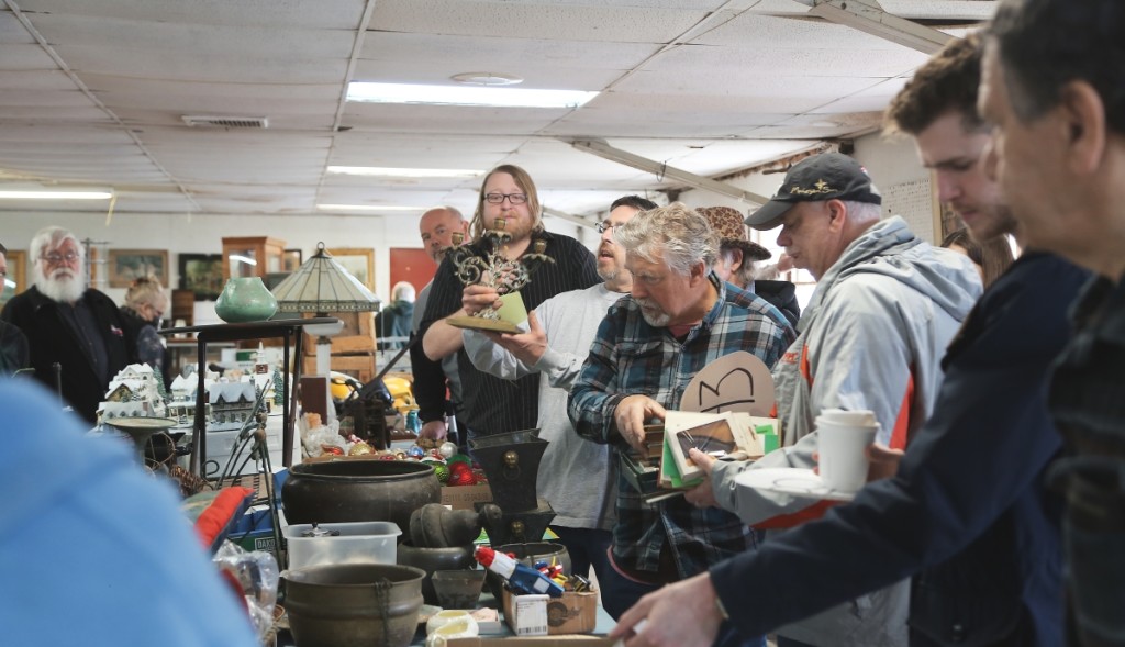 Auctioneer Dan Kingsbury, bespectacled, shown center, conducts the early bird auction, moving through vast amounts of items in a short amount of time.